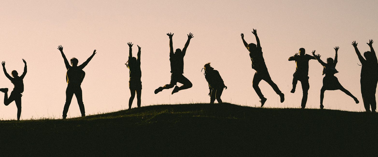 Silhouettes of people celebrating on a hilltop at sunset